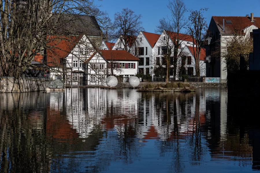 Historische Häuser spiegeln sich in einer ruhigen Wasserfläche